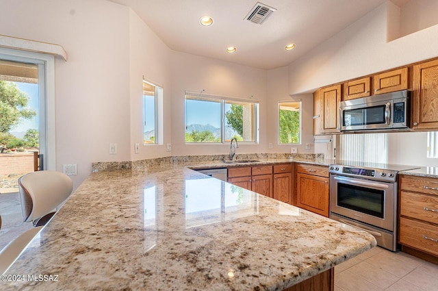 kitchen with stainless steel appliances, a sink, a peninsula, and light stone counters