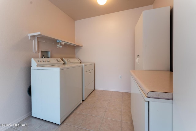 laundry area featuring washer and dryer, light tile patterned flooring, and baseboards