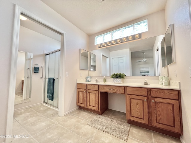 bathroom with double vanity, a closet, a stall shower, tile patterned flooring, and baseboards