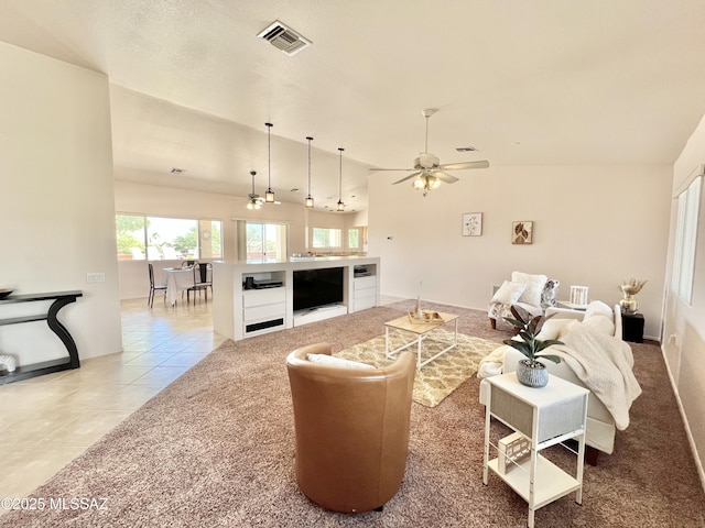 living area featuring light tile patterned floors, visible vents, vaulted ceiling, and a ceiling fan