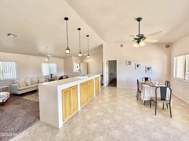 kitchen with visible vents, a ceiling fan, a kitchen island, open floor plan, and light countertops