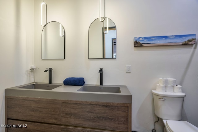 bathroom featuring double vanity, a sink, and toilet