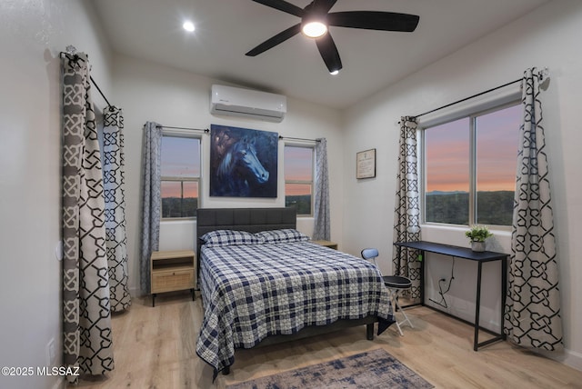 bedroom with recessed lighting, a wall unit AC, ceiling fan, and light wood-style flooring