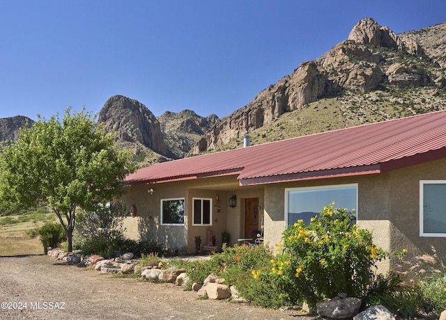 view of front facade with metal roof, stucco siding, and a mountain view