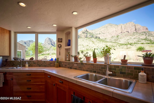 kitchen with a mountain view, a textured ceiling, sink, and decorative backsplash