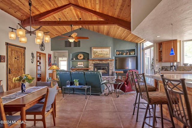 dining area featuring a stone fireplace, tile patterned floors, ceiling fan, and wooden ceiling