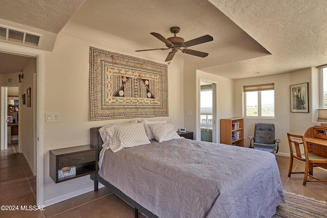bedroom featuring baseboards, a ceiling fan, visible vents, and a textured ceiling