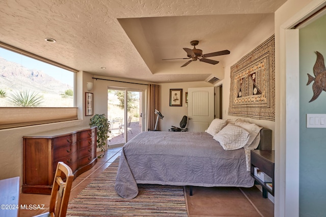 bedroom with tile patterned flooring, a mountain view, ceiling fan, access to outside, and a textured ceiling