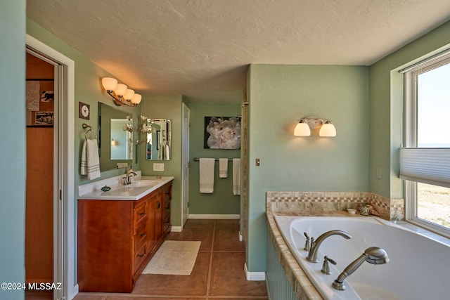 bathroom with tile patterned flooring, a washtub, vanity, and a textured ceiling