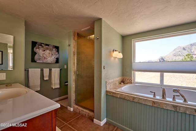 bathroom with tile patterned flooring, a mountain view, independent shower and bath, vanity, and a textured ceiling