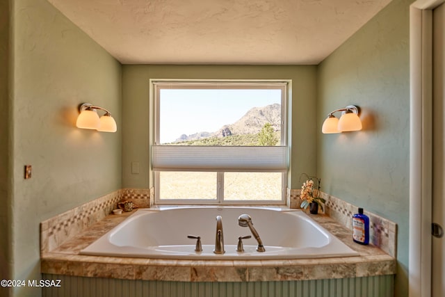 bathroom with a mountain view, a textured ceiling, and a tub to relax in