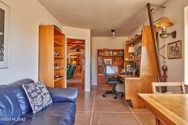 home office with tile patterned floors, a textured ceiling, and built in desk