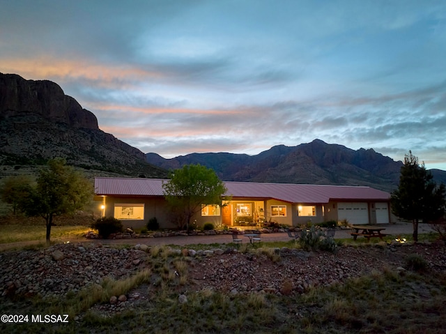 back house at dusk with a garage and a mountain view