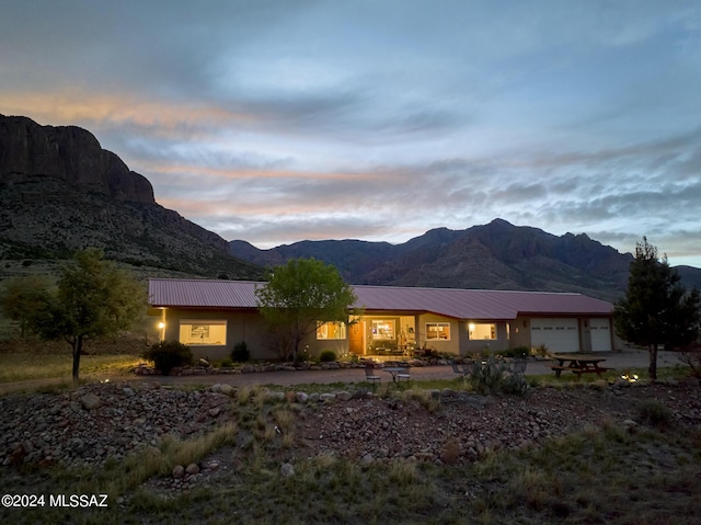 exterior space with a mountain view, a garage, stucco siding, metal roof, and driveway
