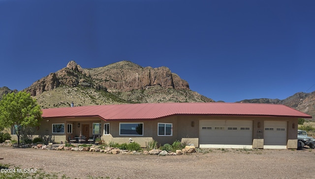 view of front of house with a mountain view, a garage, stucco siding, metal roof, and driveway