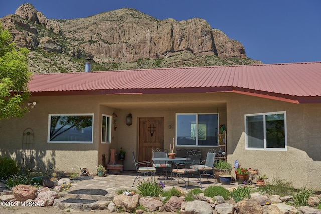 view of front of home featuring a patio area, stucco siding, metal roof, and a mountain view