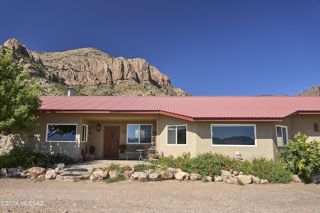 ranch-style home with metal roof, a patio area, stucco siding, and a mountain view