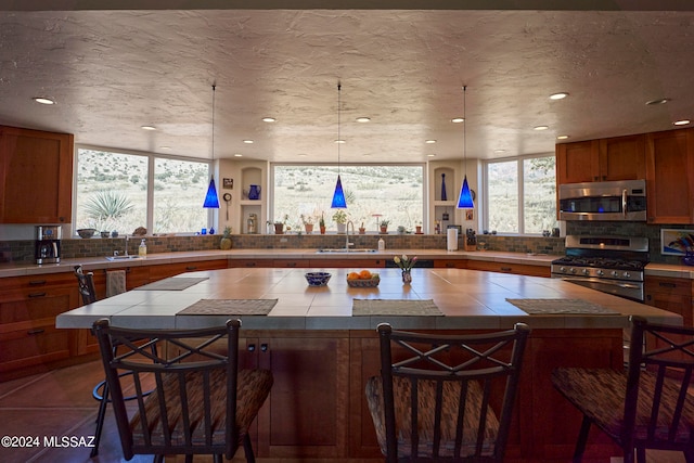 kitchen with decorative backsplash, appliances with stainless steel finishes, a healthy amount of sunlight, and a breakfast bar