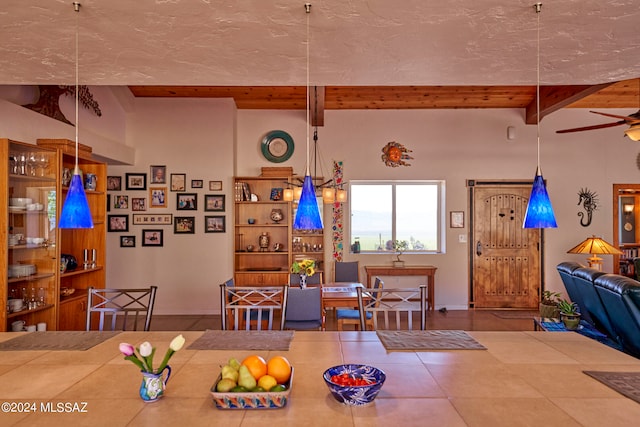 dining space with ceiling fan, a textured ceiling, and lofted ceiling with beams