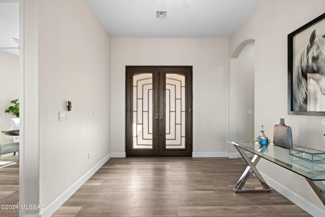 foyer entrance featuring baseboards, visible vents, wood finished floors, and arched walkways