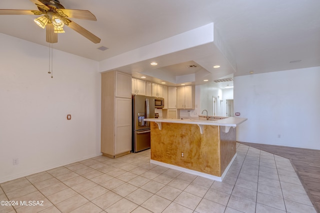 kitchen with ceiling fan, light tile floors, sink, a breakfast bar area, and appliances with stainless steel finishes