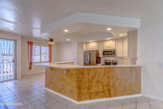 kitchen featuring appliances with stainless steel finishes, white cabinets, ceiling fan, light tile floors, and a raised ceiling