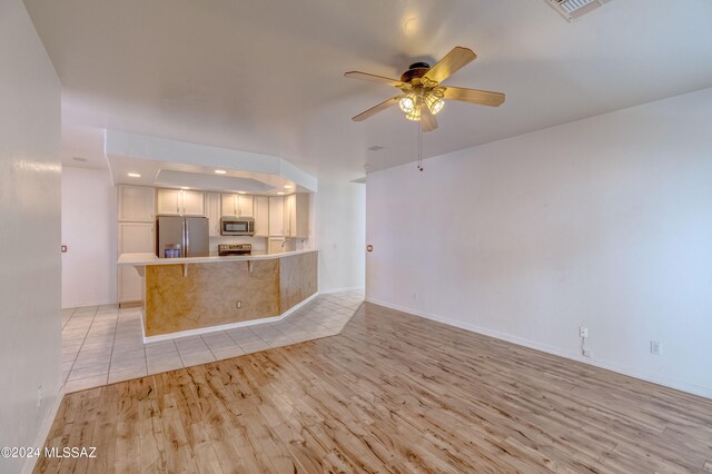 unfurnished living room with ceiling fan and light tile floors