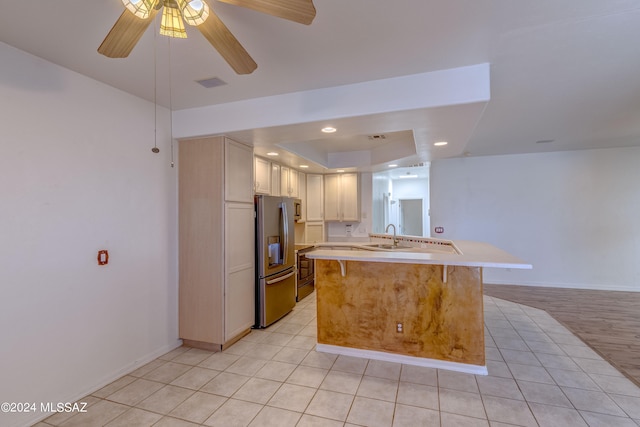 kitchen featuring ceiling fan, kitchen peninsula, light tile floors, a breakfast bar area, and stainless steel fridge with ice dispenser