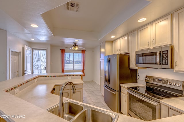 kitchen featuring ceiling fan, a tray ceiling, white cabinetry, and appliances with stainless steel finishes