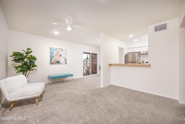 sitting room with ceiling fan and light colored carpet