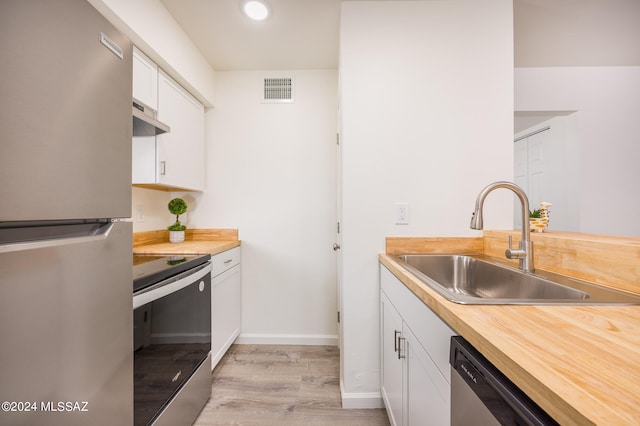 kitchen featuring light wood-type flooring, sink, white cabinets, stainless steel appliances, and butcher block countertops