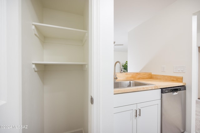 interior space with white cabinets, sink, wooden counters, and stainless steel dishwasher