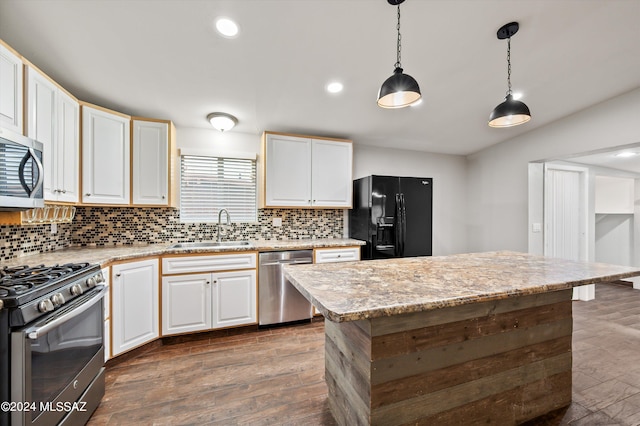 kitchen with decorative light fixtures, dark wood-type flooring, appliances with stainless steel finishes, sink, and a kitchen island