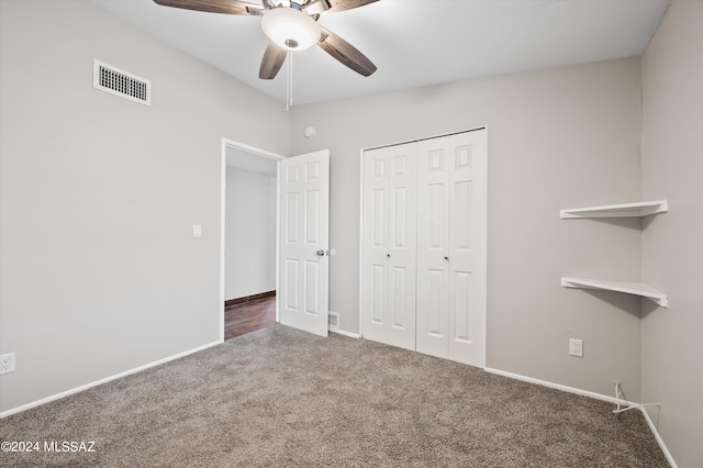 unfurnished bedroom featuring dark colored carpet, a closet, and ceiling fan