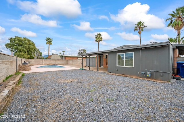 back of property featuring a patio area and a fenced in pool