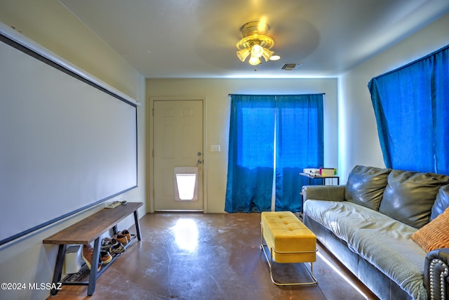 home theater featuring ceiling fan and concrete flooring