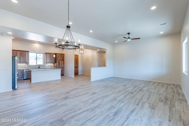 kitchen featuring ceiling fan with notable chandelier, stainless steel appliances, pendant lighting, light hardwood / wood-style floors, and a kitchen island