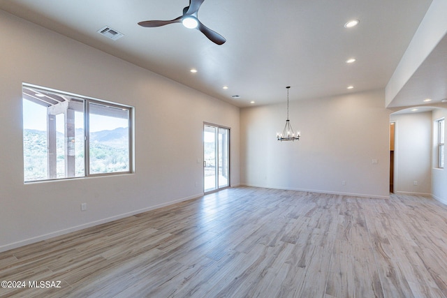 empty room featuring ceiling fan with notable chandelier and light hardwood / wood-style floors