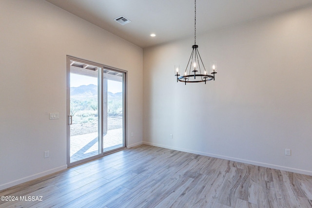 unfurnished dining area with a chandelier and light hardwood / wood-style floors