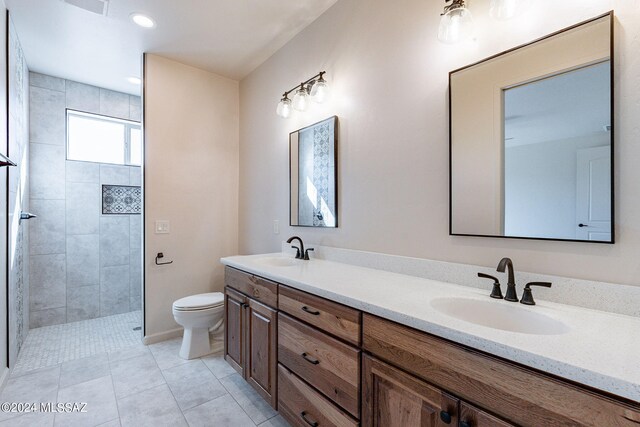 bathroom featuring tile patterned floors, vanity, toilet, and tiled shower