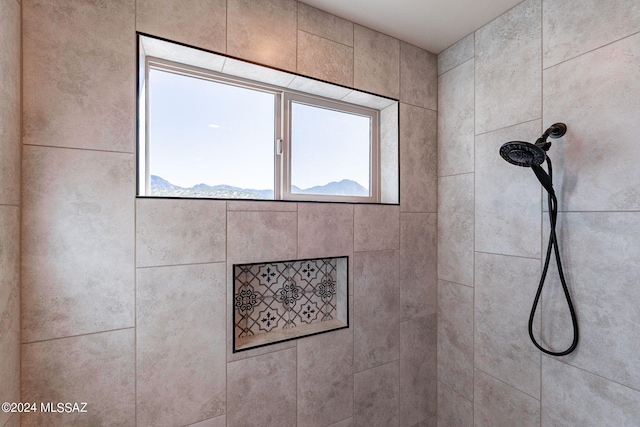 bathroom featuring a tile shower, a mountain view, and plenty of natural light