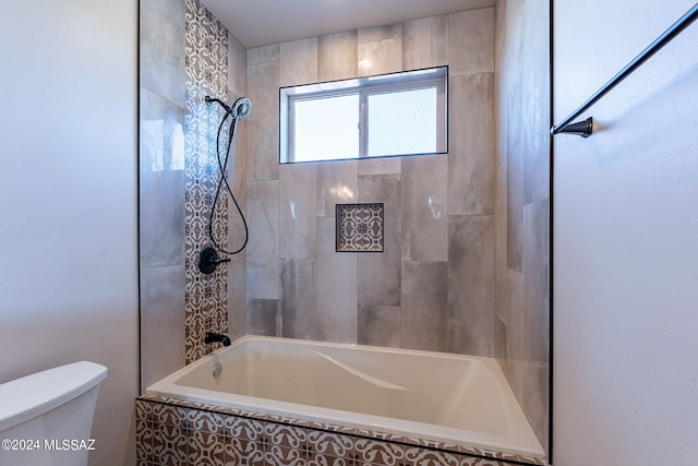 bathroom featuring toilet and tiled shower / bath