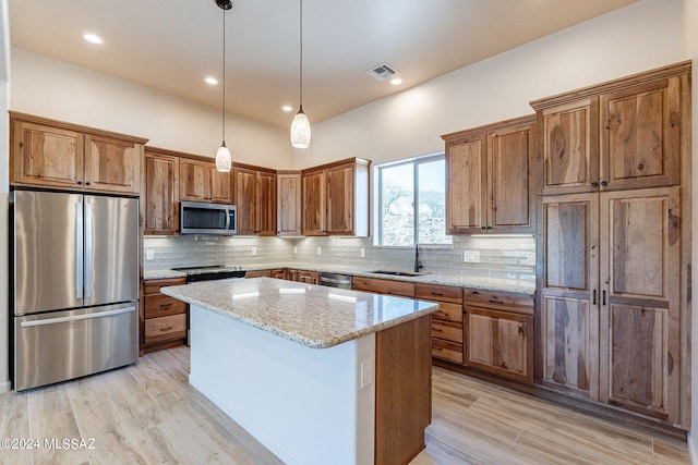 kitchen featuring decorative backsplash, light stone counters, stainless steel appliances, light hardwood / wood-style floors, and a kitchen island