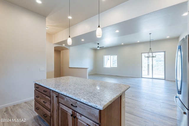 kitchen featuring stainless steel fridge, light hardwood / wood-style flooring, a kitchen island, and pendant lighting