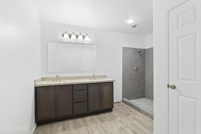 bathroom featuring hardwood / wood-style floors, vanity, and a tile shower