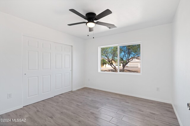 unfurnished bedroom with a closet, light hardwood / wood-style flooring, and ceiling fan