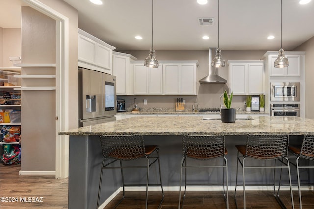 kitchen featuring wall chimney exhaust hood, decorative light fixtures, white cabinets, dark wood-type flooring, and stainless steel appliances