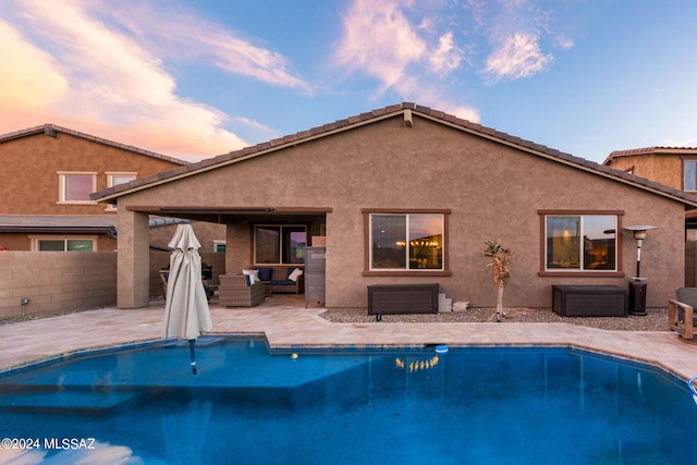 pool at dusk with a patio area and outdoor lounge area