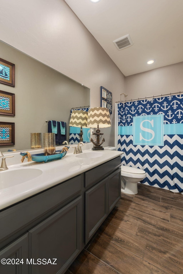 bathroom featuring hardwood / wood-style floors, toilet, and dual bowl vanity