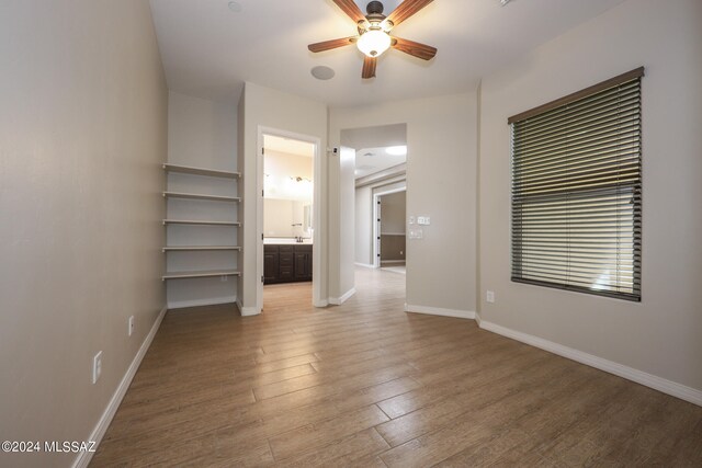 unfurnished bedroom with wood-type flooring, ceiling fan, and connected bathroom